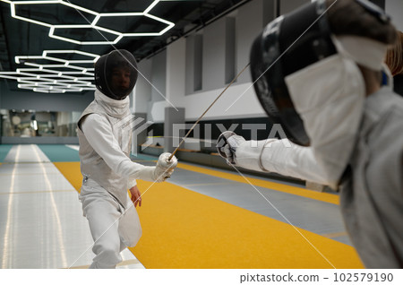Two young swordsmen in uniform practicing attack and defense during training 102579190