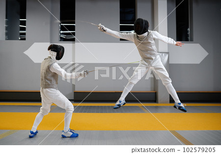 Two fencers sparring during training session in professional martial art school 102579205