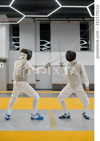 Fencing partners fighting with rapiers practicing attack and defense combination Fencing partners fighting with rapiers practicing attack and defense combination 102579212