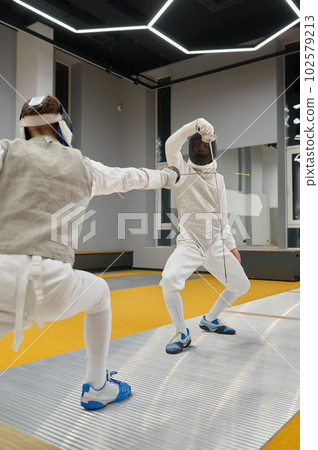 Two swordsmen exercising and fighting with rapiers during fencing competition Two swordsmen exercising and fighting with rapiers during fencing competition 102579213