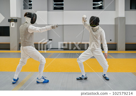 Two swordsmen exercising and fighting with rapiers during fencing competition Two swordsmen exercising and fighting with rapiers during fencing competition 102579214