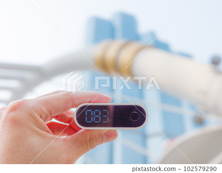 Hand holding air quality meter outdoor with background of blue edifice. 102579290