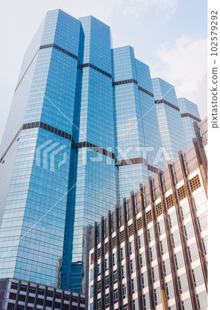 Morning sunlight reflecting on shiny windows of blue building. 102579292