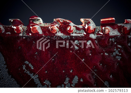 detail of the teeth of a bloody chainsaw blade background 102579313