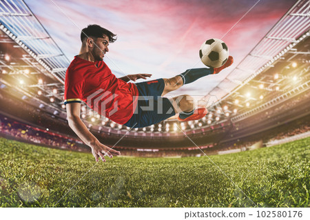 Soccer striker hits the ball with an acrobatic kick in the air at the stadium 102580176