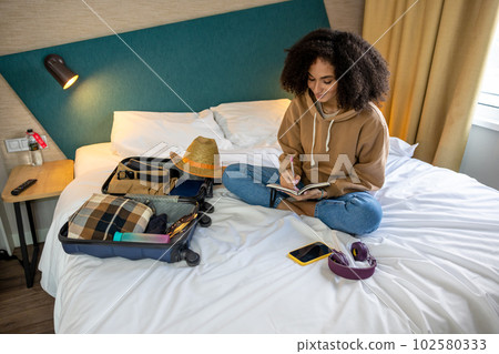 Young curly-haired woman getting ready for vacation and looking contented 102580333