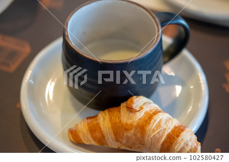 Croissant, a buttery pastry with truffle soup in a cup. Croissant, a buttery pastry with truffle soup in a cup. 102580427