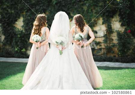 Bride with bridesmaids holding wonderful luxury wedding bouquet of different flowers on the wedding day 102580861