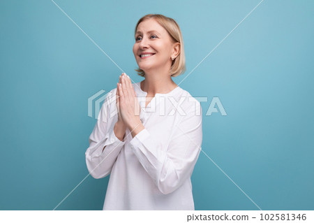 blond mature woman in white blouse praying with a smile blond mature woman in white blouse praying with a smile 102581346