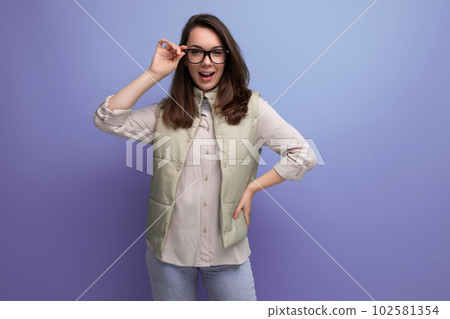 young brunette woman holding glasses in her hands on a studio background with copy space young brunette woman holding glasses in her hands on a studio background with copy space 102581354