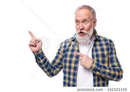 senior pensioner gray-haired man with a beard in a shirt shows his index finger to the side on a 102581356