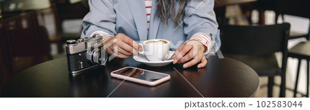 Modern lady sitting with coffee at coffee shop 102583044