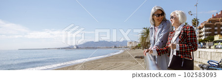 Cheerful mature ladies relaxing outdoors at coastline Cheerful mature ladies relaxing outdoors at coastline 102583093