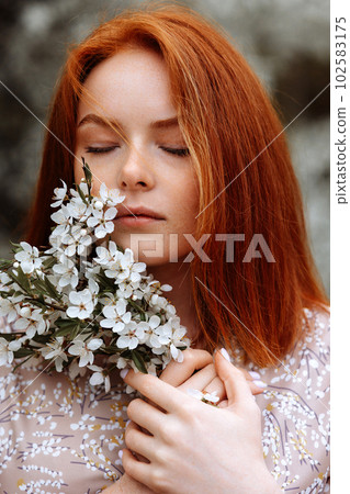 Woman in a dress on a background of white flowers of an apple tree Woman in a dress on a background of white flowers of an apple tree 102583175