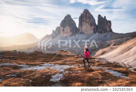 Walking girl with backpack on the trail in mountains at sunset 102585363