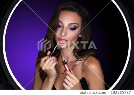 Female portrait of a young brunette with a beautiful evening make-up, with purple shadows on her eyes 102585727