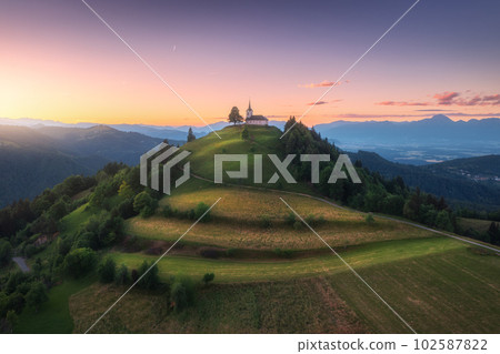 Aerial view of small church on the mountain peak at sunset 102587822