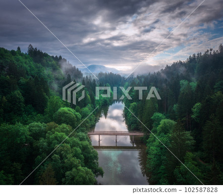 Aerial view of wooden bridge over the river in mountains at dawn 102587828