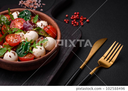Delicious fresh salad with mozzarella cheese, cherry tomatoes, herbs, salt and spices Delicious fresh salad with mozzarella cheese, cherry tomatoes, herbs, salt and spices 102588496