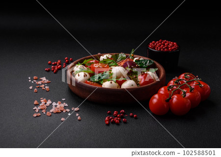 Delicious fresh salad with mozzarella cheese, cherry tomatoes, herbs, salt and spices 102588501