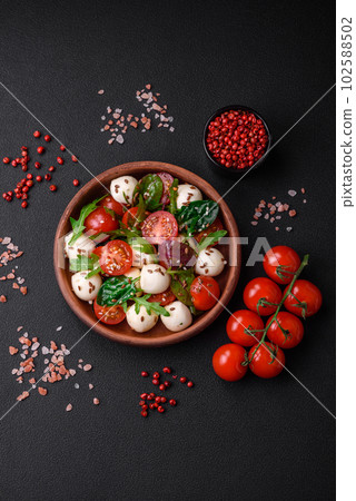 Delicious fresh salad with mozzarella cheese, cherry tomatoes, herbs, salt and spices 102588502