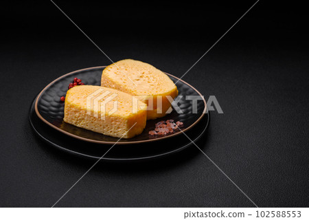 Delicious porous yellow cheese cut in large pieces on a ceramic plate Delicious porous yellow cheese cut in large pieces on a ceramic plate 102588553