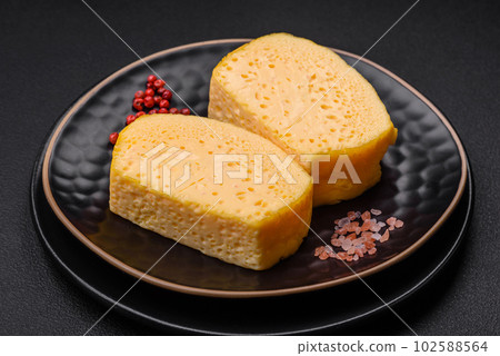 Delicious porous yellow cheese cut in large pieces on a ceramic plate Delicious porous yellow cheese cut in large pieces on a ceramic plate 102588564