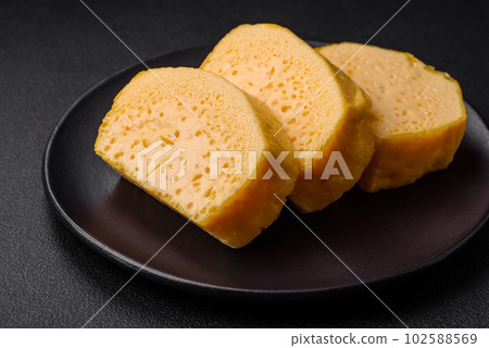 Delicious porous yellow cheese cut in large pieces on a ceramic plate Delicious porous yellow cheese cut in large pieces on a ceramic plate 102588569