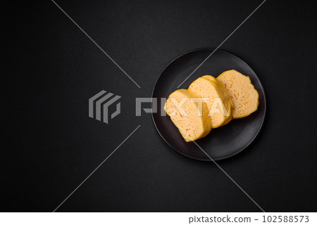 Delicious porous yellow cheese cut in large pieces on a ceramic plate 102588573