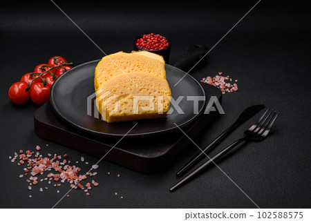 Delicious porous yellow cheese cut in large pieces on a ceramic plate 102588575