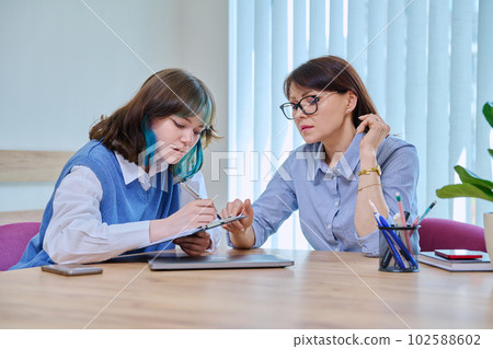 Teenage girl college student talking with counselor, psychologist in office Teenage girl college student talking with counselor, psychologist in office 102588602