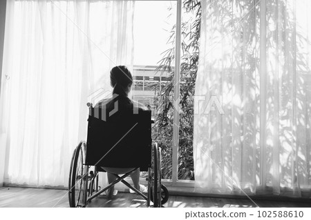 The woman sitting on wheelchair. She is see window with patient bed in hospital.disabled person lonely. Photo concept depression and Patient. The woman sitting on wheelchair. She is see window with patient bed in hospital.disabled person lonely. Photo concept depression and Patient. 102588610