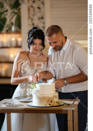 newlyweds happily cut and taste the wedding cake newlyweds happily cut and taste the wedding cake 102589486