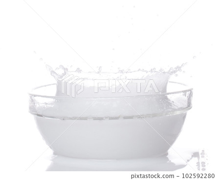 Milk yogurt white water spill splash from bowl up. Milk lotion pour float in mid air. Milk moisturizer explosion throw fluttering. White background isolated high speed shutter freeze motion Milk yogurt white water spill splash from bowl up. Milk lotion pour float in mid air. Milk moisturizer explosion throw fluttering. White background isolated high speed shutter freeze motion 102592280