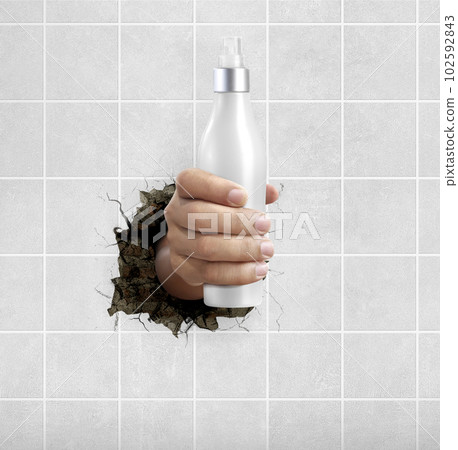 Human hand holding a cosmetics bottle through the wall with cracks Human hand holding a cosmetics bottle through the wall with cracks 102592843