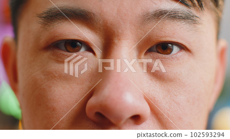 Close-up macro portrait of asian man face smiling, brown gauy eyes looking at camera blink wink Close-up macro portrait of asian man face smiling, brown gauy eyes looking at camera blink wink 102593294
