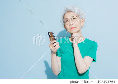 A gray-haired woman looking at her smartphone 102593764