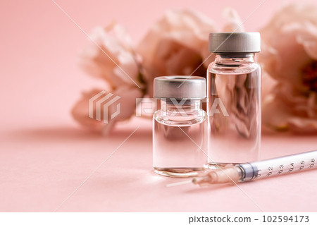粉紅色背景上的注射器和小瓶化妝品醫學圖像素材 102594173