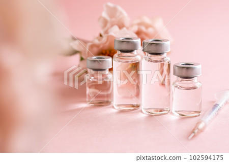 粉紅色背景上的注射器和小瓶化妝品醫學圖像素材 102594175