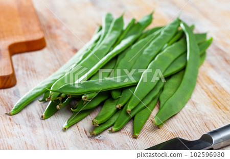 Green curly beans on a wooden surface 102596980
