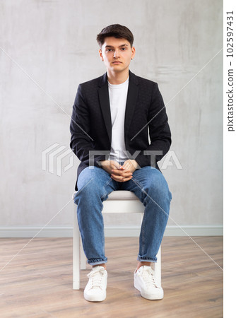 Charismatic young man sitting on chair in the middle of the room 102597431