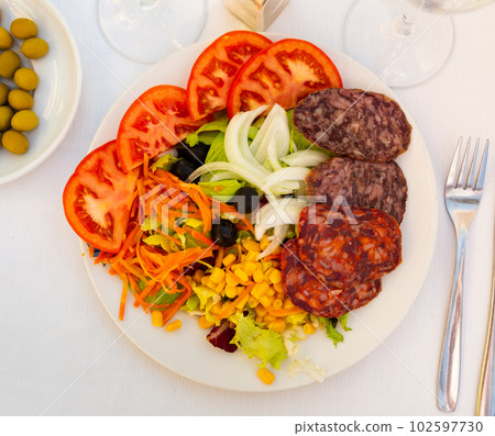 Catalan salad with lettuce, tomato, olives and various sausages 102597730