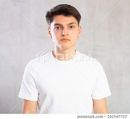 Confident young man posing against background of grey unicolored wall Confident young man posing against background of grey unicolored wall 102597737