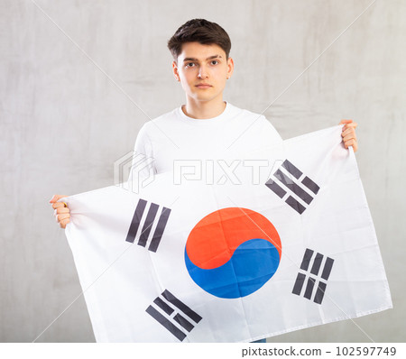 Focused young guy holding South Korea flag Focused young guy holding South Korea flag 102597749