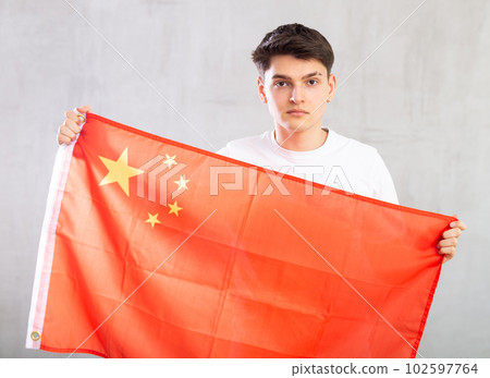 Focused young guy holding China flag 102597764