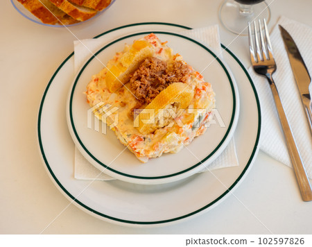 Ensalada rusa - salad with potatoes, tuna, green pea, olives and egg in plate 102597826