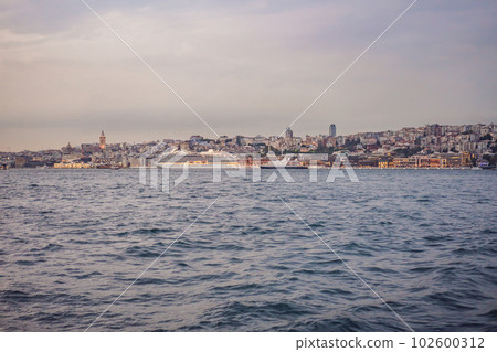 Huge cruise ship docked at terminal of Galataport, located along shore of Bosphorus strait, in Karakoy neighbourhood, with Galata tower in the background 102600312