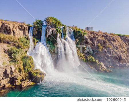 Lower Duden Falls drop off a rocky cliff falling from about 40 m into the Mediterranean Sea in amazing water clouds. Tourism and travel destination photo in Antalya, Turkey. Turkiye. 102600945