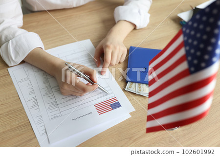 Young woman fills in visa application form near USA flag 102601992