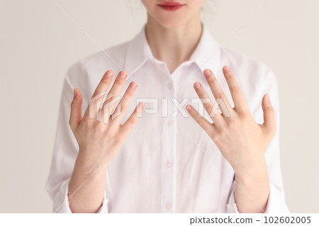 Young woman in white blouse shows hands to dermatologist 102602005